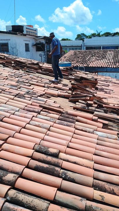 Profissional sobre telhado colonial durante a revisão das telhas